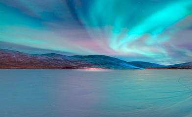 Northern lights (Aurora borealis) in the sky with super full moon - Tromso, Norway 