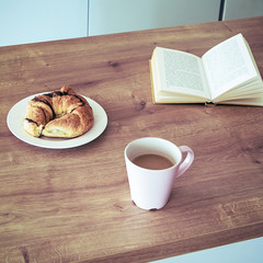 Coffee latte, book and croissant on wooden table. Still life