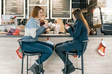 Young women drinking coffee in cafe, girls sitting near the bar counter