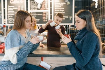 Young women drinking coffee in cafe, girls sitting near the bar counter