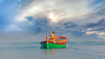 Fisherman with fishing boat in a calm sea in the background approaching stormy clouds