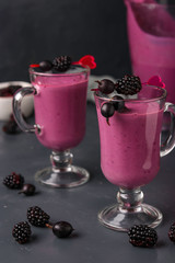 Smoothies with blackberries and gooseberry in glass on a dark background, vertical photo