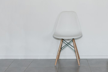 Stylish white chair near white wall in room. White office chair. Minimalist interior. Copy space.