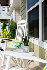 White rocking chair and side table with aloe vera plant, outdoor front porch decor close up