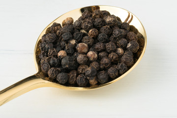 Black Peppercorns on a Gold Spoon