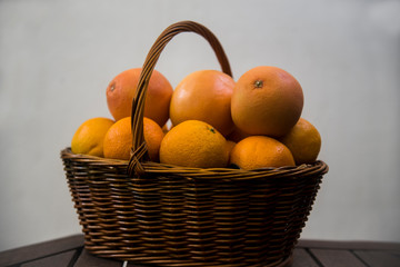 wicker basket with oranges and grapefruits on white background