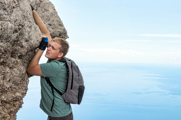 Fototapeta premium Young man hanging on edge, climbs up the rock