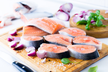 Raw salmon steaks and fillet on wooden cutting board