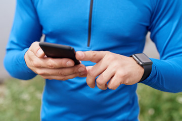 Close up of man hands syncing smart watch and phone outdoor