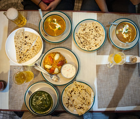 Typical nepalese meal and beer in Pokhara restaurant, Himalayas, Nepal. Assorted indian nepalese food on table. Dishes and appetizers of indian cuisine. Curry, butter chicken, rice, lentils, paneer