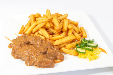Chicken skewers served with a tasty peanut sauce and French fries