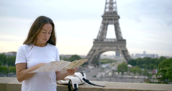 woman in t-shirt learns map against Eiffel Tower slow motion