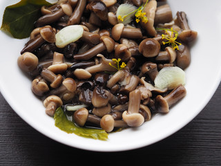 Delicious and beautiful marinated mushrooms with spices in a white plate on a dark background.  Home recipe pickles - mushrooms with garlic and herbs close-up.