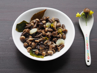Tasty and nice marinated mushrooms with spices in a white plate on a dark background.  Home recipe pickles - mushrooms with garlic and herbs close-up.