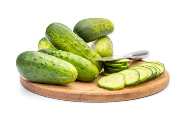 Cutted and whole cucumbers with knife on cutting board..