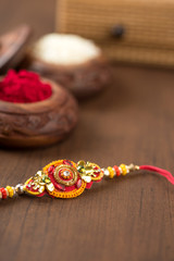 Indian festival: Raksha Bandhan background with an elegant Rakhi, Rice Grains and Kumkum. A traditional Indian wrist band which is a symbol of love between Brothers and Sisters.