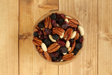 Mix of  black raisins jumbo, pecan nuts, cranberries, almonds without peel in bamboo bowl on wooden table. Closeup