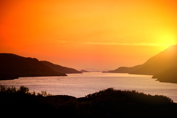Naklejka premium Beautiful sunset view of Connemara region in Ireland. Scenic Irish countryside landscape with magnificent mountains on the horizon, County Galway, Ireland.