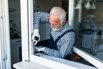 Senior handyman fixing window. Renovation.