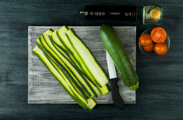 Zucchini in the background. Fried young sliced courgettes in a pan on a dark background. The view from the top. Copy space