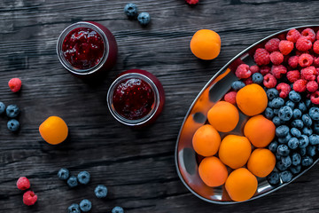 Fruit and berry smoothies. Fresh apricots, raspberries and blueberries on an oval metal plate. Brown background.