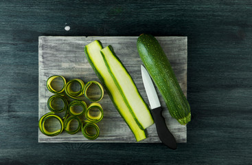 Zucchini in the background. Fried young sliced courgettes in a pan on a dark background. The view from the top. Copy space
