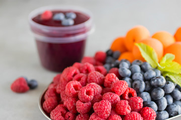 Fruit and berry smoothies. Fresh apricots, raspberries and blueberries on an oval metal plate. Gray background.