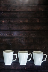 3 coffee mugs on a wooden table background - morning pick me up drink