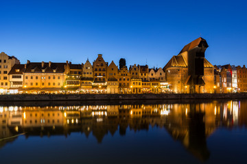 Naklejka premium Scenic view of the lit Crane and other old buildings along the Long Bridge waterfront at the Main Town in Gdansk, Poland, in the evening.