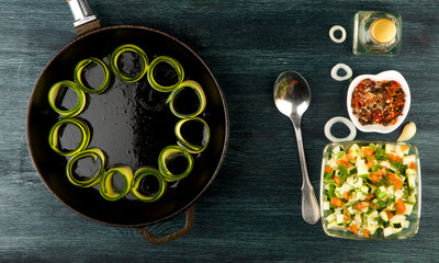 Zucchini in the background. Fried young sliced courgettes in a pan on a dark background. The view from the top. Copy space