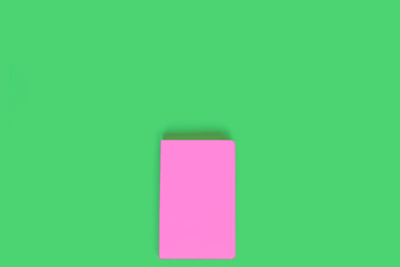 Pink closed notebook on light green background