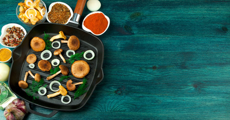 Fresh mushrooms with spices and herbs on black board. View from above. Copy space.