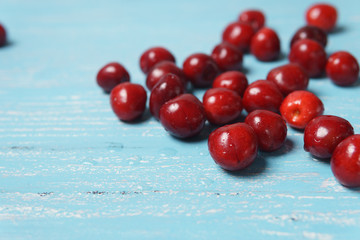Red sweet cherry scattered on a turquoise wooden table