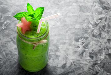 Tropical cocktail. Smoothie with mint, slices of watermelon and ice cubes on a gray concrete surface. View from above. Copy space