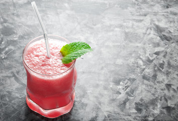Tropical cocktail. Smoothie with mint, slices of watermelon and ice cubes on a gray concrete surface. View from above. Copy space