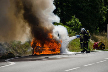 France road, July 22, 2014. Firefighters putting out a fire from a burning car