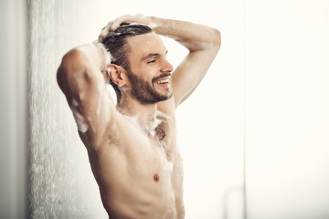 Handsome bearded man lather his well-muscled body