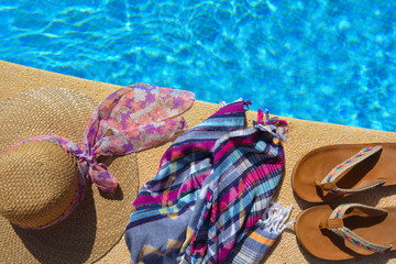 straw hat, beach wrap and sandals at the poolside.