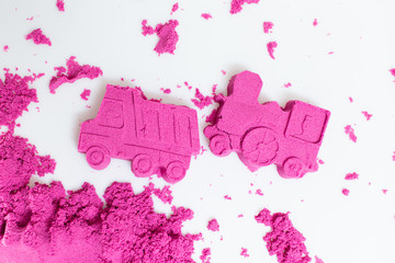 Truck and train made with a pink kinetic sand on a white background.