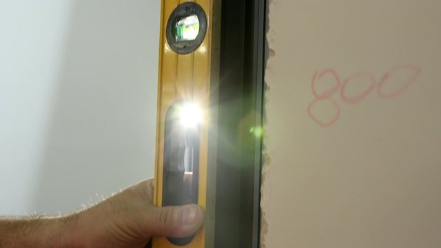 in the hand of the line level of the Clinometer bubbles to measure the evenness of the wall. rays of light enter the chamber. slow motion. close up