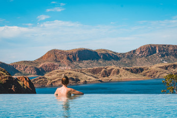 Fototapeta na wymiar woman looking landscape in infinity pool