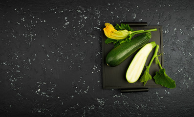 Fresh green zucchini on a dark table. The view from the top. Copy space.