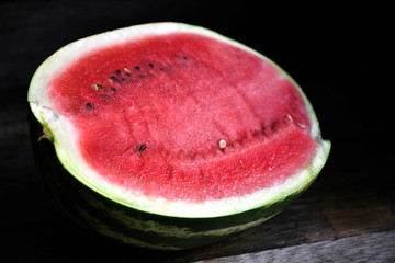 A watermelon cut in half, on an old rustic table.