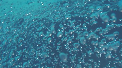 Bubbles rising to the water surface. Slow motion. Air bubbles in clear blue water (underwater shot), good for backgrounds.