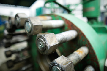 Shallow depth of field image with worn out heavy iron industrial equipment used in the oil and gas drilling industry (rusty bolts, nuts, pipes, levers)
