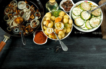 Vegetables on the background. Fried zucchini sauce in a plate. Young boiled potatoes with dill in a bowl. Fried chanterelle mushrooms with golden onions in a frying pan. copy space