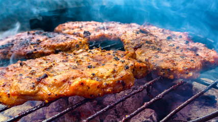 Assorted delicious grilled meat on a barbecue . Selective focus of juicy tasty steaks grilling on barbecue grill grade with flame . 