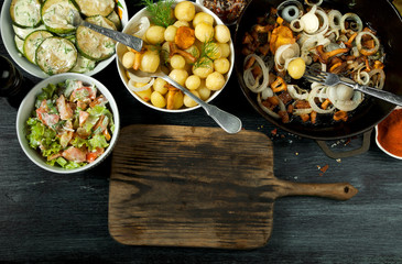 Vegetables on the background. Fried zucchini sauce in a plate. Young boiled potatoes with dill in a bowl. Fried chanterelle mushrooms with golden onions in a frying pan. copy space