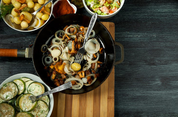 Vegetables on the background. Fried zucchini sauce in a plate. Young boiled potatoes with dill in a bowl. Fried chanterelle mushrooms with golden onions in a frying pan. copy space