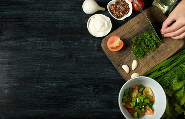 Salad with vegetables. View from above. Fresh salad in a plate on a dark background. Garlic, tomato, cucumber, dill and onion in a dish of dark surface. Copy space.